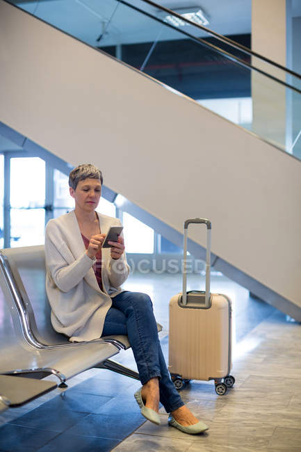 Woman using mobile phone in waiting area at airport terminal — Stock Photo