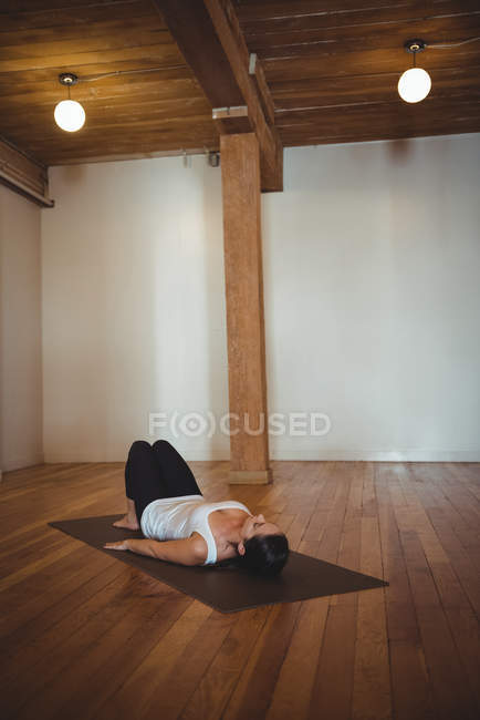 Woman practicing yoga on mat in fitness studio — Stock Photo