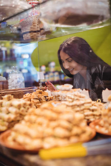 Schöne Frau betrachtet türkische Süßigkeiten, die im Geschäft ausgestellt sind — Stockfoto