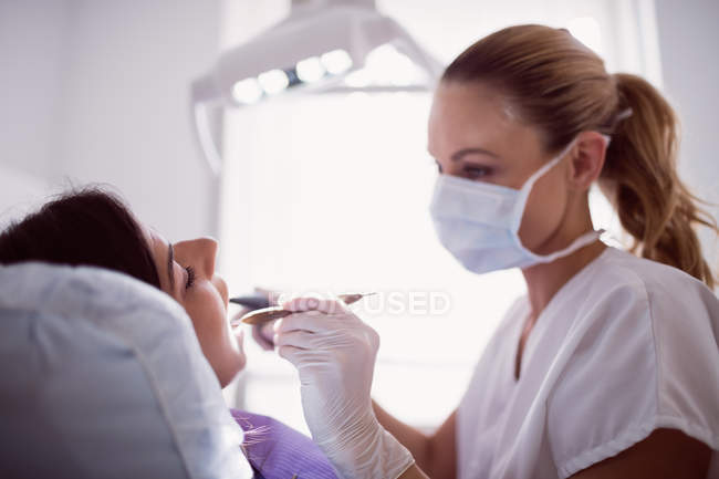 Dentista examinando paciente feminina na clínica — Fotografia de Stock