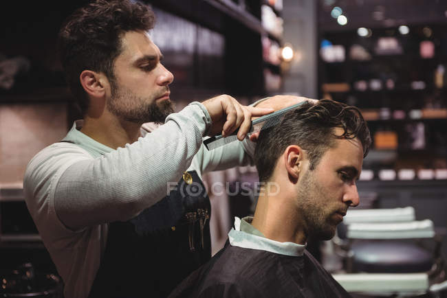 Hairdresser combing client hair in barber shop — Stock Photo