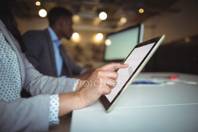 Средняя секция бизнесвумен с помощью цифрового планшета в офисе — стоковое фото