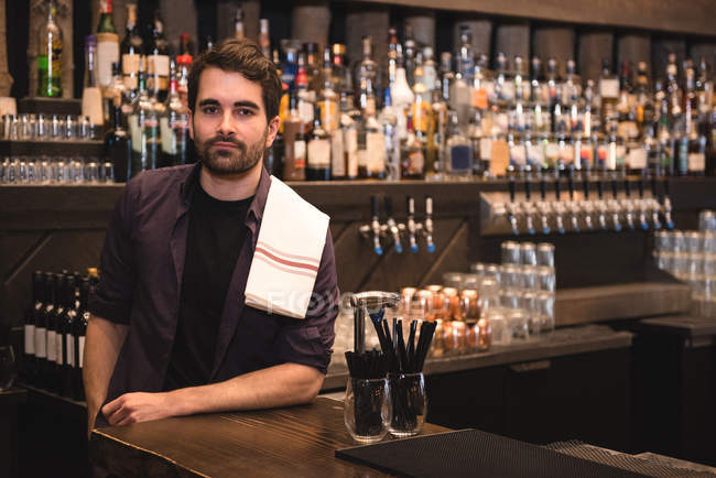 Ritratto di un barista sicuro in piedi al bancone del bar — Foto stock