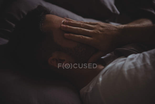 Gros plan de l'homme frottant les yeux pendant qu'il dormait dans son lit à la maison — Photo de stock