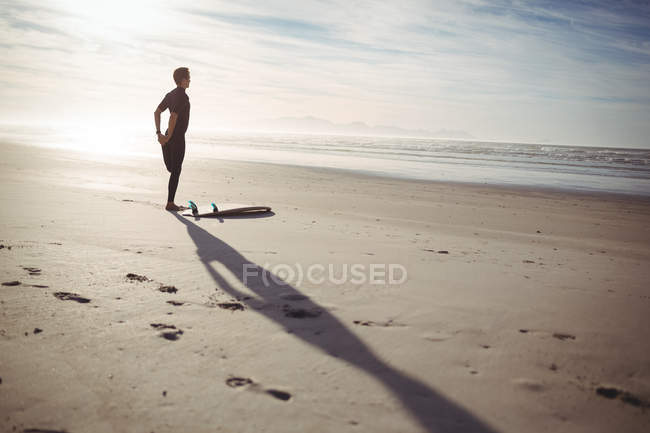 Fit man with surfboard exercising on beach — Stock Photo