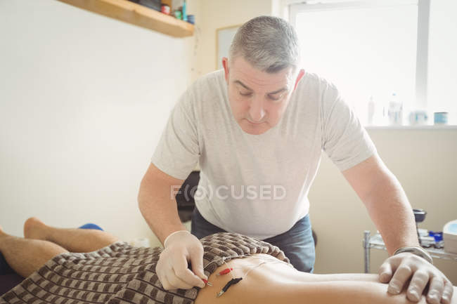 Physiotherapist inserting needle on patient for electro dry needling in clinic — Stock Photo