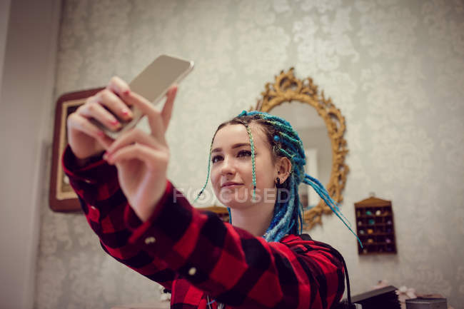 Woman with dreadlocks taking a selfie on her mobile phone in salon — Stock Photo