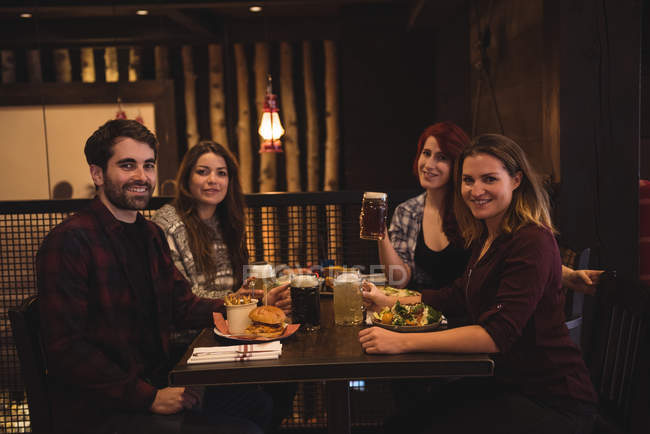 Счастливые друзья наслаждаются едой вместе в баре — стоковое фото