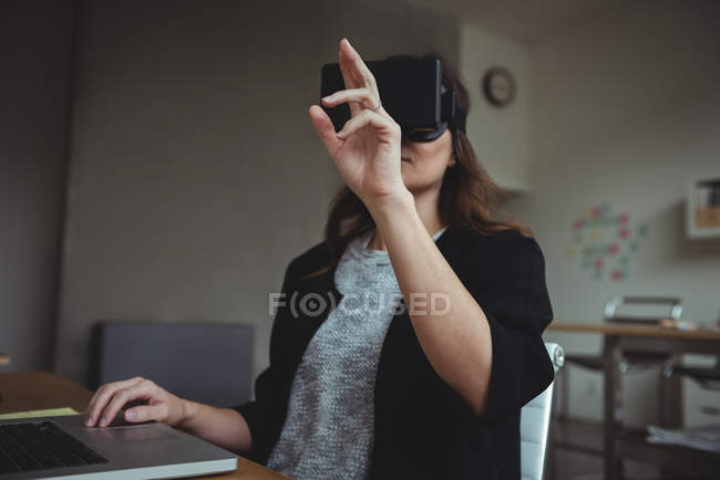 Executivo de negócios feminino usando fone de ouvido de realidade virtual no escritório — Fotografia de Stock