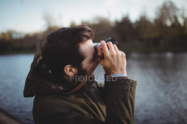 Человек, снимающий с камеры возле реки — стоковое фото