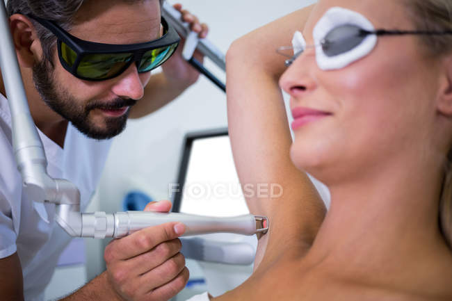 Dermatologist removing hair of patient armpit in beauty salon — Stock Photo