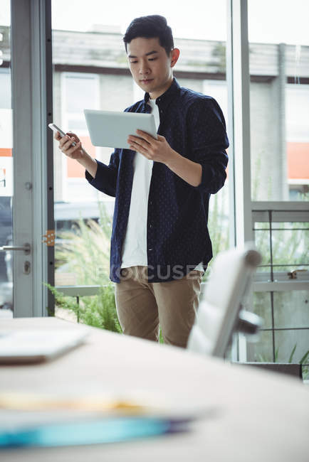 Бизнес-руководитель с помощью мобильного телефона и цифрового планшета в офисе — стоковое фото