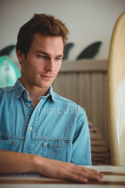 Homme sélectionnant une planche de surf en bois dans un magasin — Photo de stock