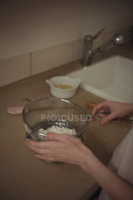 Mani di donna che sforzano lo zucchero a velo in cucina — Foto stock