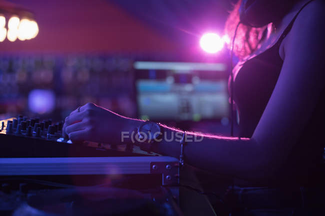 Female dj mixing music on mixing console in bar — Stock Photo