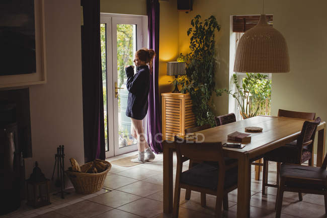 Femme réfléchie prenant un café à la maison — Photo de stock