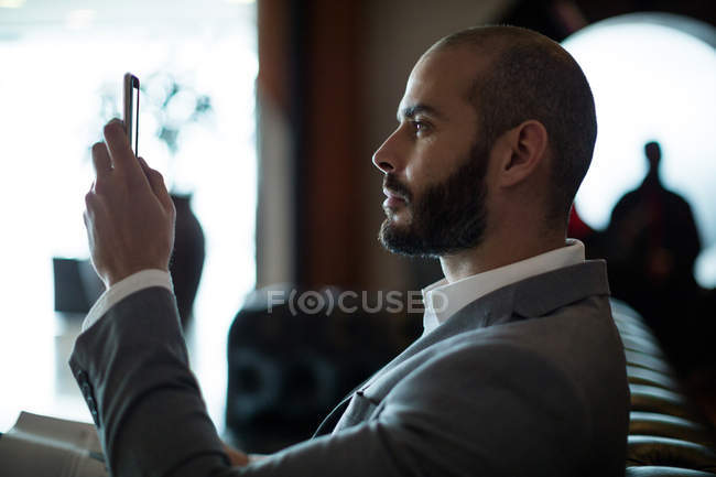 Businessman using mobile phone in waiting area at airport terminal — Stock Photo