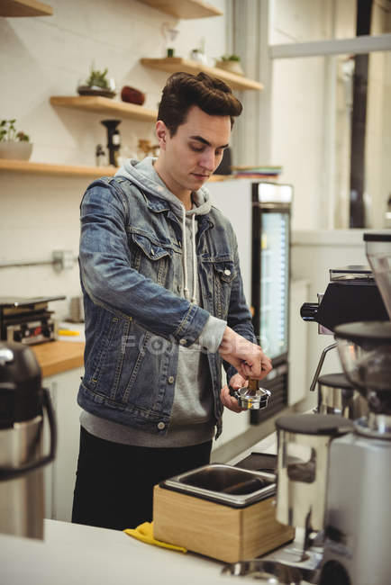 Чоловік пресує каву з тампоном у портативному фільтрі в кав'ярні — стокове фото