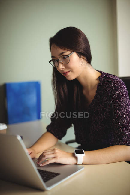 Молодая предпринимательница, работающая над ноутбуком в офисе — стоковое фото