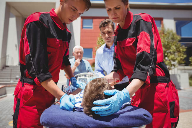 Paramedics examining injured boy on street — Stock Photo