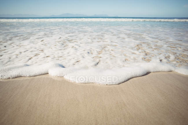Gros plan sur les vagues d'eau de mer sur une plage de sable — Photo de stock