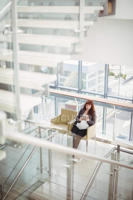 Вагітна бізнес-леді використовує цифровий планшет біля коридору в офісі — стокове фото