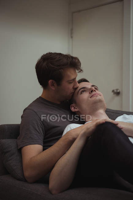 Romantisches homosexuelles Paar umarmt sich auf dem Sofa im Wohnzimmer zu Hause — Stockfoto