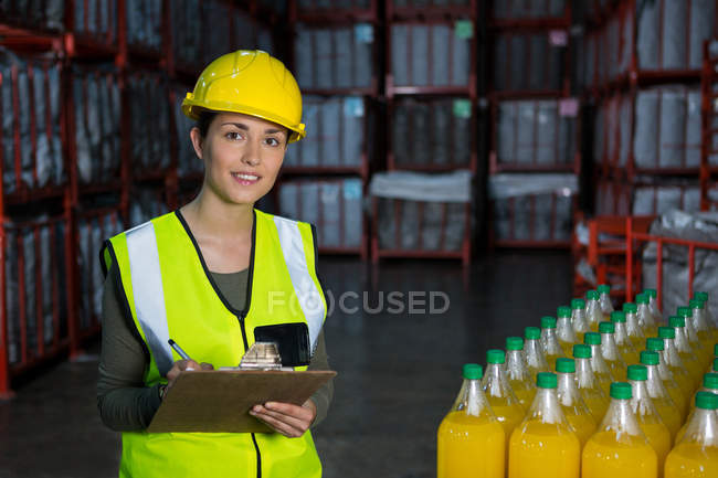 Jeune ouvrière vérifiant les bouteilles de jus dans l'usine — Photo de stock