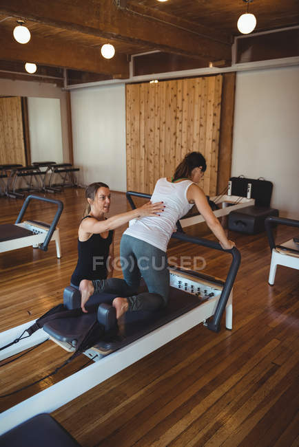 Instrutor assistindo uma mulher enquanto pratica pilates no estúdio de fitness — Fotografia de Stock