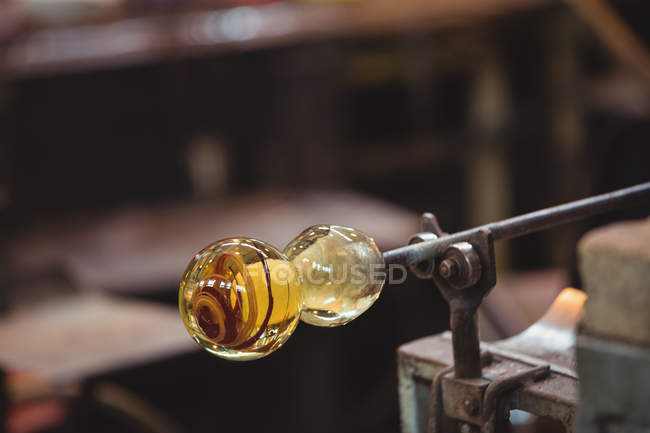 Primer plano del vidrio fundido en la tubería de soplado en la mesa de marver en la fábrica de soplado de vidrio - foto de stock