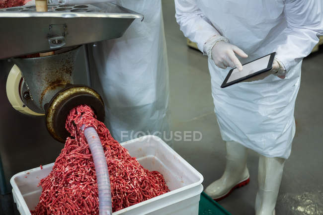 Fresh minced meat in mincing machine at meat factory — Stock Photo