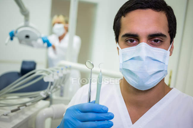 Retrato de dentista segurando ferramentas dentárias na clínica odontológica — Fotografia de Stock