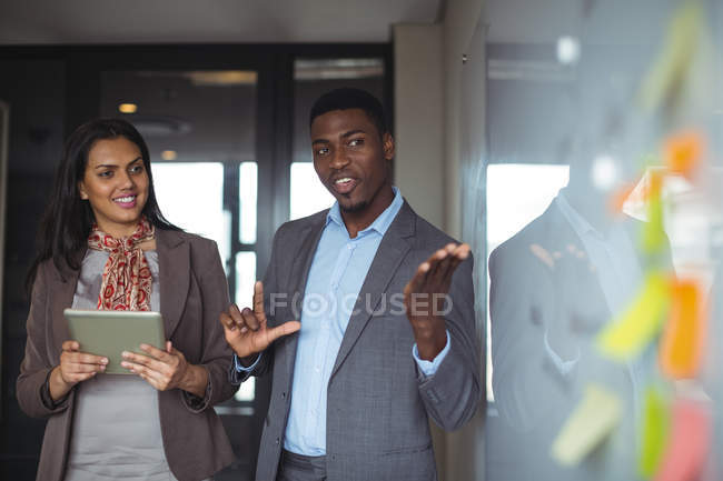 Бизнесмен обсуждает на белой доске с коллегой в офисе — стоковое фото