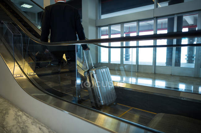 Vista trasera del hombre de negocios en escalera mecánica en el aeropuerto — Stock Photo