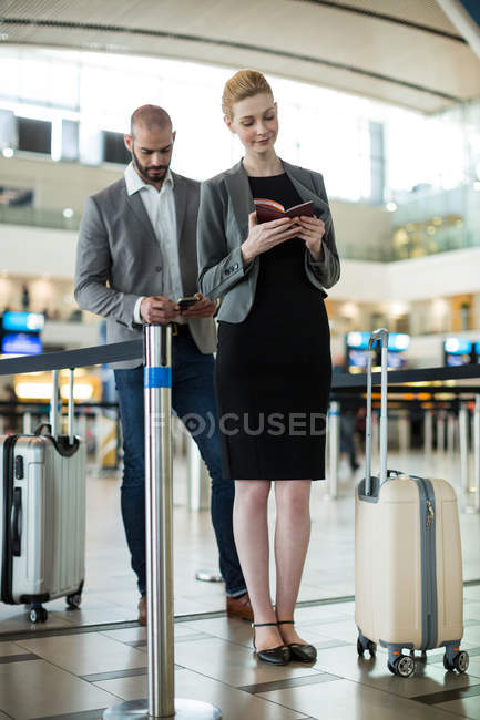 Gente de negocios esperando en cola en un mostrador de facturación con equipaje en la terminal del aeropuerto — Stock Photo