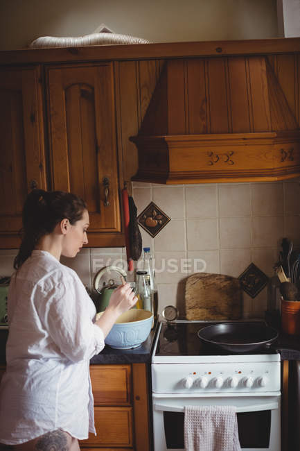 Mujer de pie y preparando la comida en la cocina en casa - foto de stock