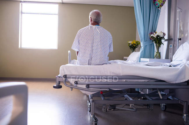Paciente idoso do sexo masculino pensativo sentado na enfermaria do hospital — Fotografia de Stock