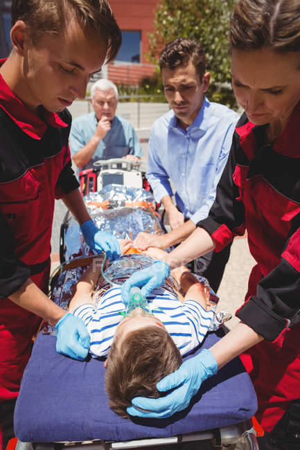 Paramédicos examinando menino ferido na rua — Fotografia de Stock