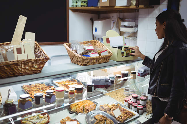 Frau sucht verpackte Lebensmittel an Lebensmitteltheke im Supermarkt aus — Stockfoto
