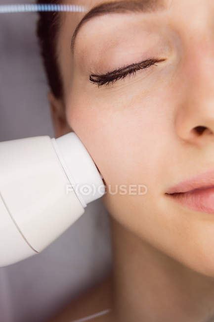 Dermatologist giving facial massage to patient through sonic lifting in clinic — Stock Photo