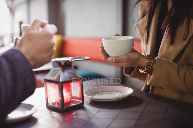 Середина пари, що тримає чашки кави в ресторані — стокове фото