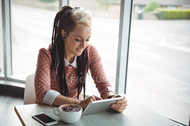 Женщина с цифровым планшетом во время чашки кофе в кафе — стоковое фото