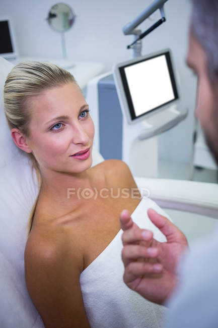 Paciente mujer acostada y mirando al médico en la clínica - foto de stock