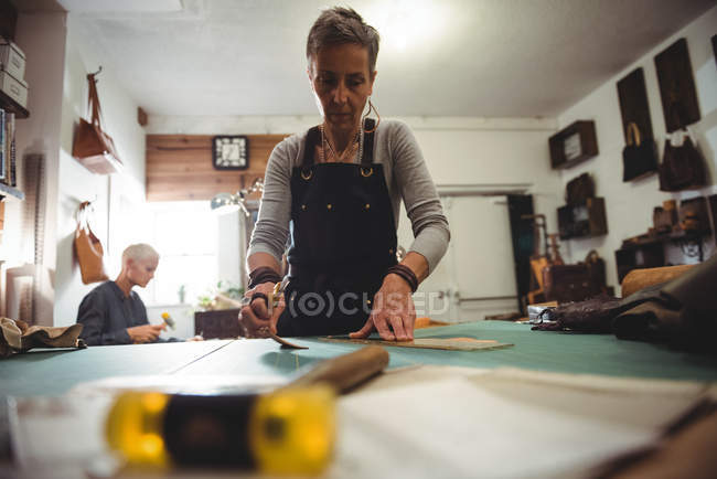 Attentive craftswoman working on a piece of leather in workshop — Stock Photo