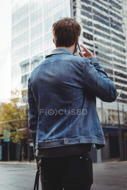 Вид сзади на человека, разговаривающего по мобильному телефону, стоя на улице — стоковое фото