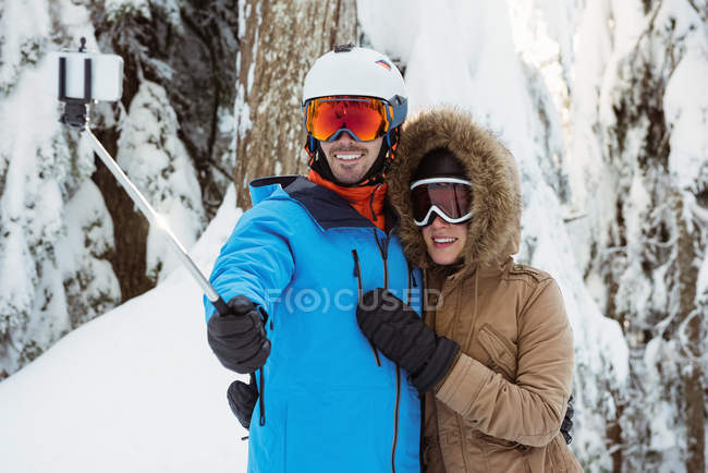 Couple skieur heureux prenant un selfie sur un paysage enneigé — Photo de stock