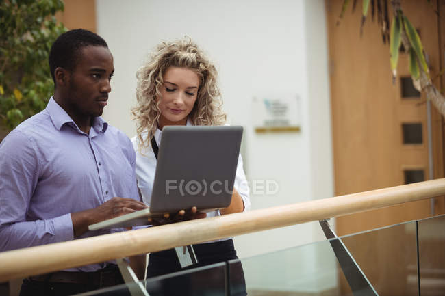 Керівники бізнесу обговорюють ноутбук в офісному коридорі — стокове фото