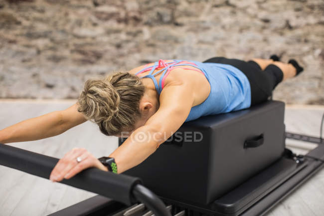Mujer ejercitándose en reformador en gimnasio - foto de stock