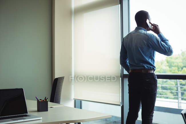 Business executive talking on mobile phone in office — Stock Photo