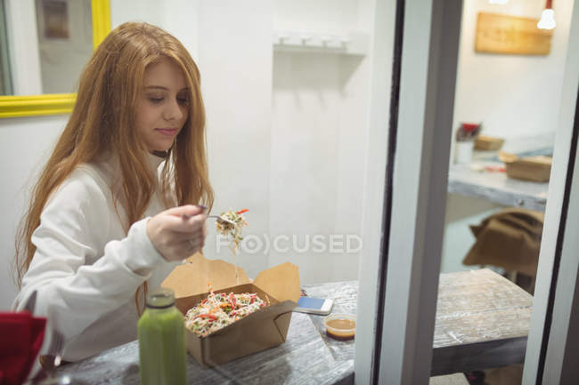 Mujer joven comiendo ensalada en el restaurante - foto de stock